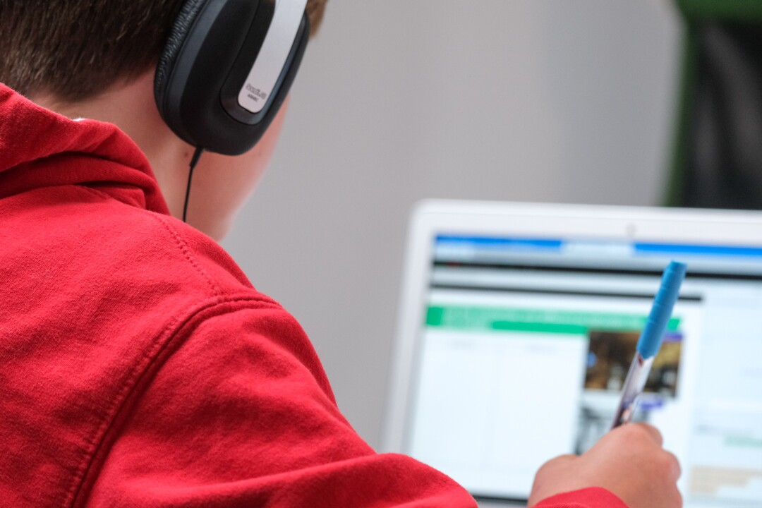 Person wearing headphones using computer with pen